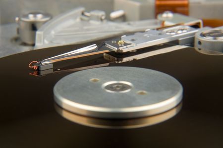 Macro view of the inner workings of a hard disk drive which shows the disk and recording head.