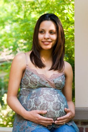 A beautiful young pregnant Hispanic woman relaxing outside white waiting for the birth of her .の写真素材