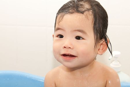 Baby taking bath in blue tubの写真素材
