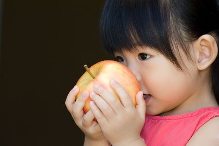 Little child hold a red apple close to her faceの写真素材