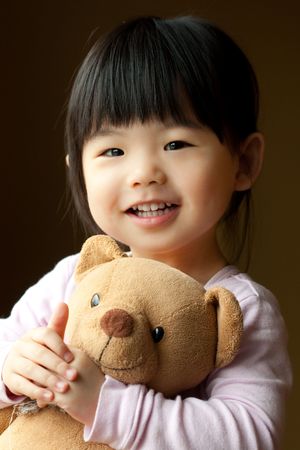 Smiling little child holding a teddy bear in her handの写真素材
