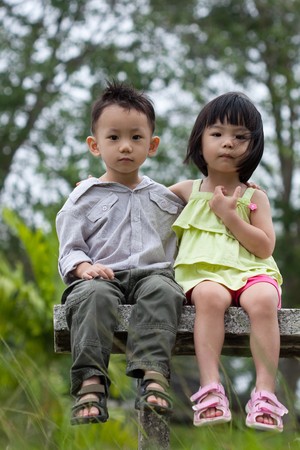 Two little kids dating with hand lifts onto shoulder in a parkの写真素材