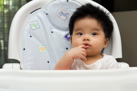 Portrait of a little Asian baby girl sits on a high chairの写真素材