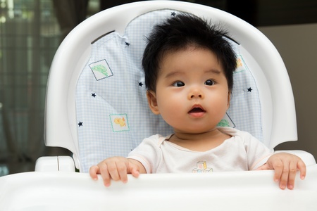Portrait of a little Asian baby girl sits on a high chairの写真素材