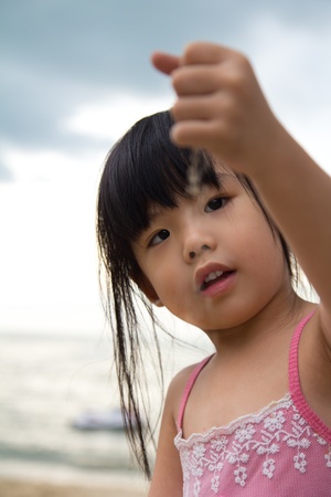 Little girl hold a handful sand in her hand and dropping it slowlyの写真素材