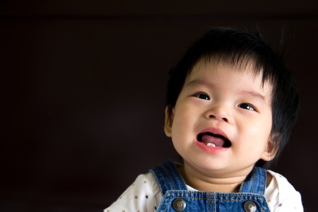Happy little baby girl smiling isolated in black backgroundの写真素材