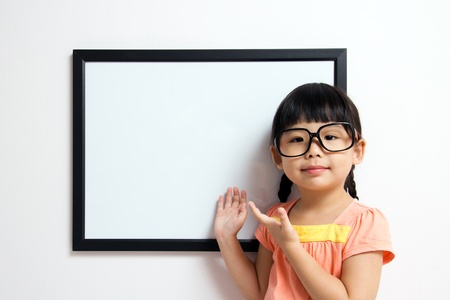 School girl wears a big spectacles posing next to a white boardの写真素材