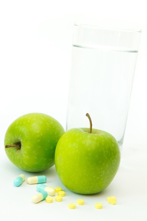 Green apples with slimming capsules and glass of mineral waterの写真素材