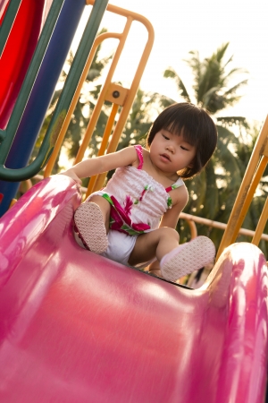 Child plays on slide in an outdoor playgroundの写真素材