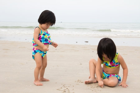 Two little girls plays sand on beachの写真素材