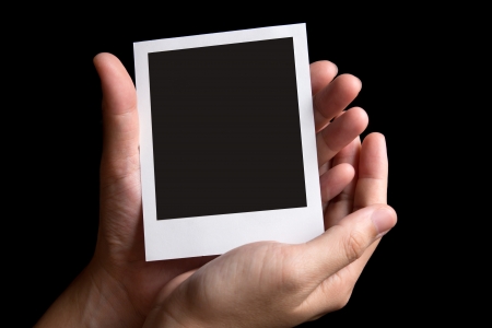 Blank instant photo frame in palm isolated in black backgroundの写真素材