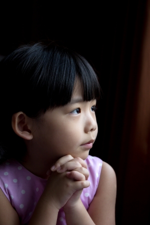 Little child is making a wish isolated in dark backgroundの写真素材