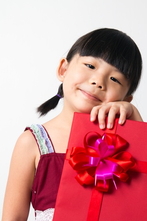 Portrait of Asian child girl with red gift box represents Christmas themeの写真素材