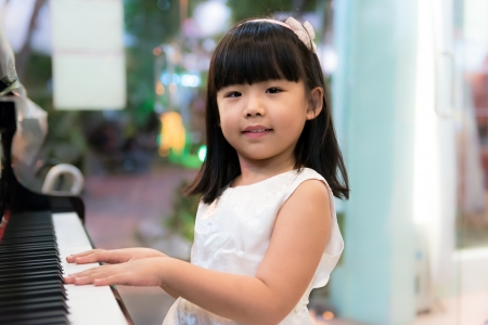 Happy little Asian girl is playing pianoの写真素材