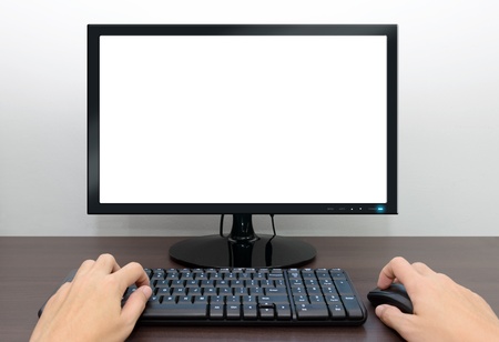 Closeup image of blank monitor and male hands over the computer keyboard and mouseの写真素材