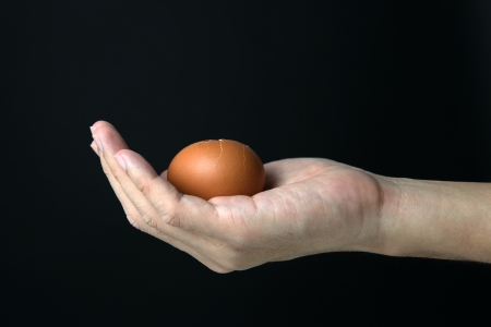 Hand hold egg isolated on black backgroundの写真素材
