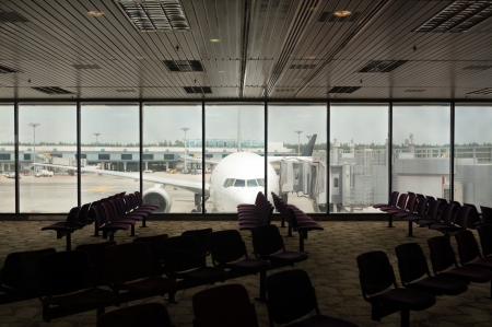 Parked airplane on an airport view through the boarding room windowの写真素材