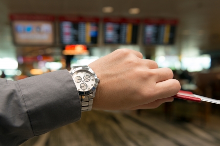 Hand hold a passport, transit pass and ticket checking time to departの写真素材