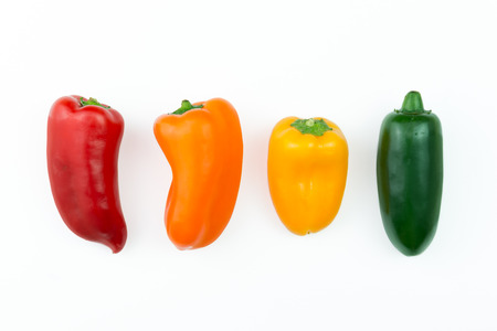 Red, orange, yellow and green jalapeno pepper in a rowの写真素材