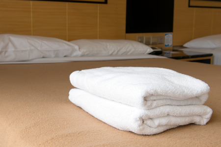 Bath towels on the bed of hotel bedroomの写真素材