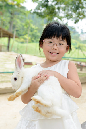 Portrait of Asian toddler girl holding white rabbitの写真素材