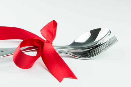 Fork, knife and spoon tied up with red ribbon on white backgroundの写真素材