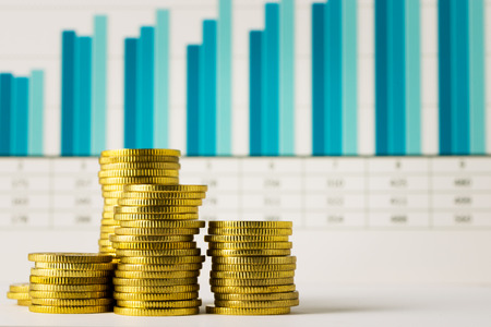 Stacks of gold coins with financial chartの写真素材