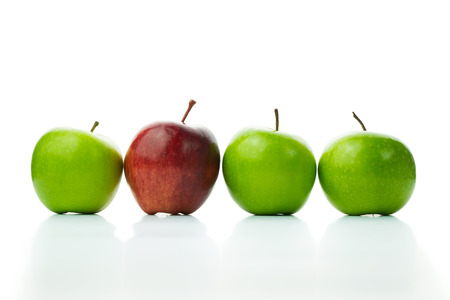 Red apple standing out in a row of green applesの写真素材