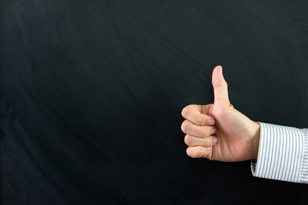 Hand showing thumb up in front of chalkboardの写真素材
