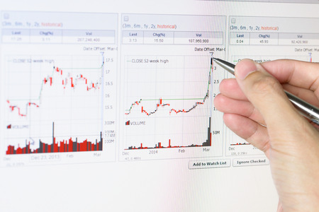 Close up of hand holding pen pointing graph chart on monitorの写真素材