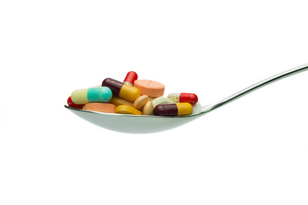Spoon full of variety medicine pills isolated on white backgroundの写真素材