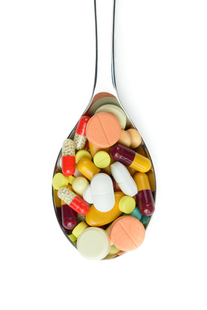 Spoon full of variety medicine pills isolated on white backgroundの写真素材