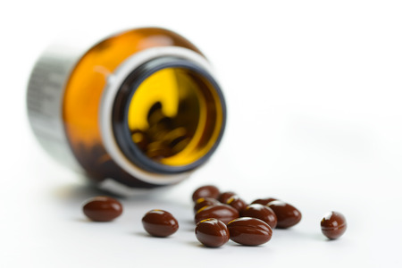 Medicine pills spill out of a bottle isolated on white backgroundの写真素材
