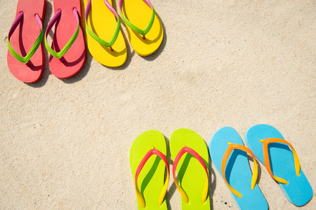 Four pairs of beach sandals on white sandの写真素材