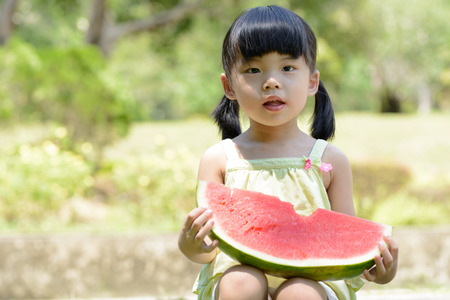 Little Asian baby eating watermelon in parkの写真素材