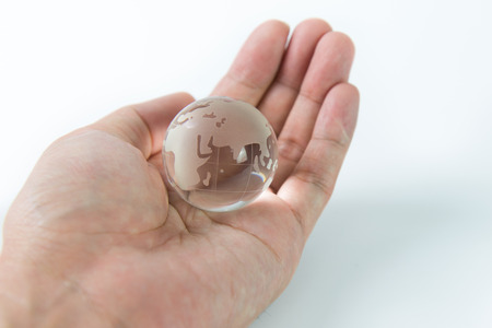 Glass earth globe on hand palm white on backgroundの写真素材