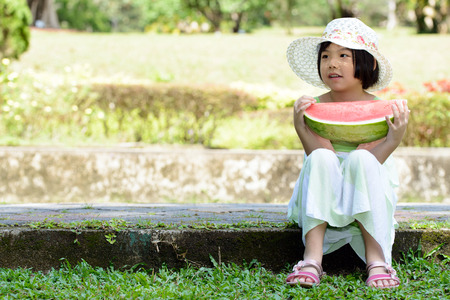 Smiling Asian kid with a piece of watermelon in parkの写真素材