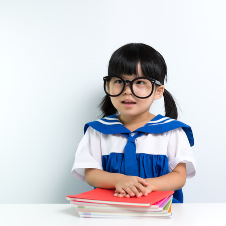 Little Asian girl wearing eyeglasses with booksの写真素材