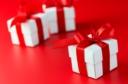 Three white gift boxes with ribbons on red background