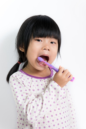 Little Asian girl in pyjamas brushing teethの写真素材
