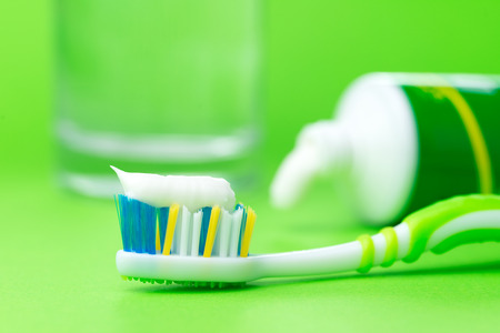 Close up of toothbrush and toothpaste tube on green backgroundの写真素材