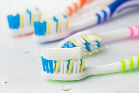 Multicolor toothbrushes with toothpaste on the green on white background