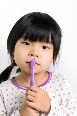 Little Asian girl in pyjamas holding toothbrushの写真素材