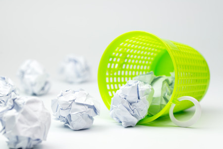 Green trash bin and crumpled paper balls on white backgroundの写真素材
