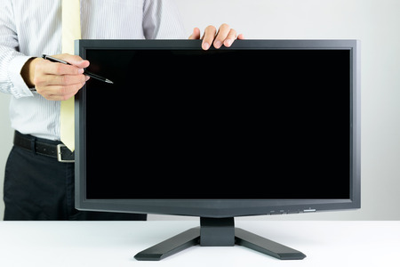 Businessman with pen pointing at blank monitor screenの写真素材
