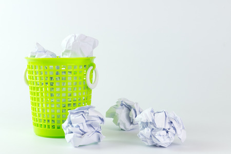 Green trash bin and crumpled paper balls on white backgroundの写真素材