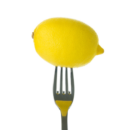 Whole lemon on fork over white backgroundの写真素材