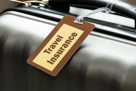 Travel insurance luggage tag tied to a suitcaseの写真素材