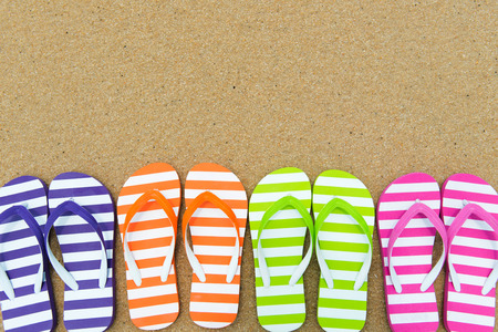 Close up of multicolor flip flips on sandの写真素材