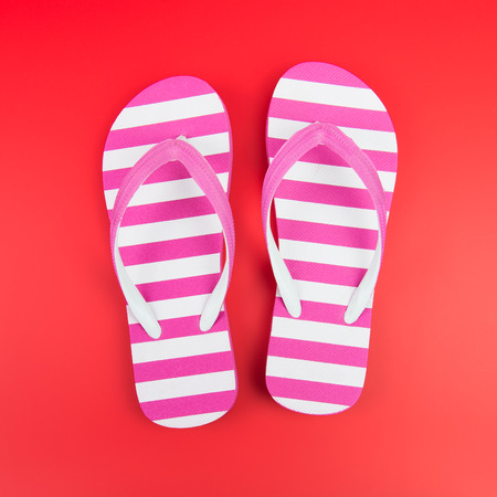 Pair of pink striped flip flop on red backgroundの写真素材